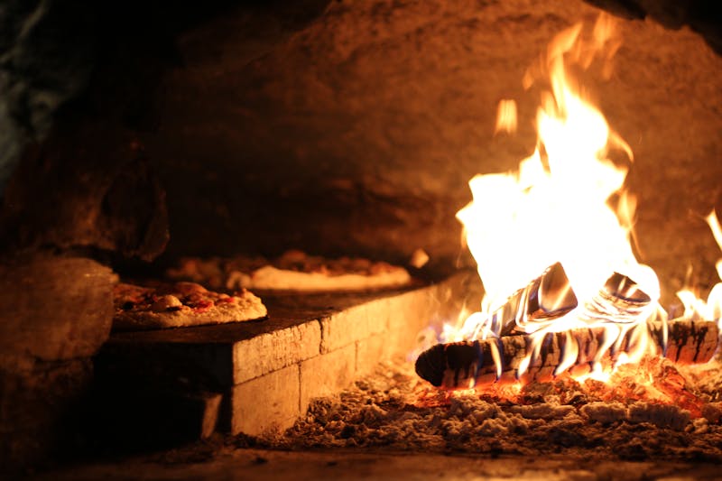 Pizza factory wood-fired oven with fresh pizzas being prepared